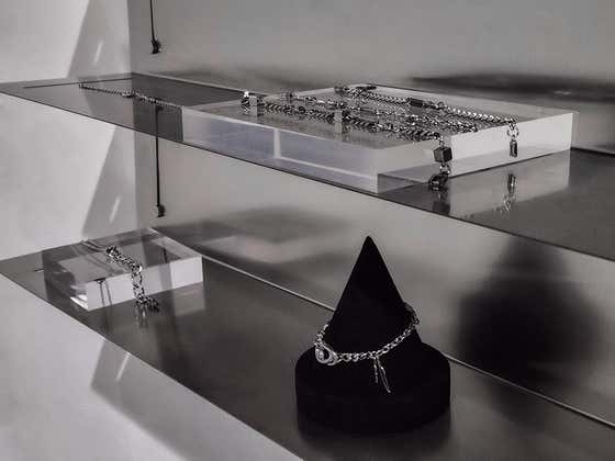 Silver jewelry displayed on acrylic plinths and brushed metal shelves