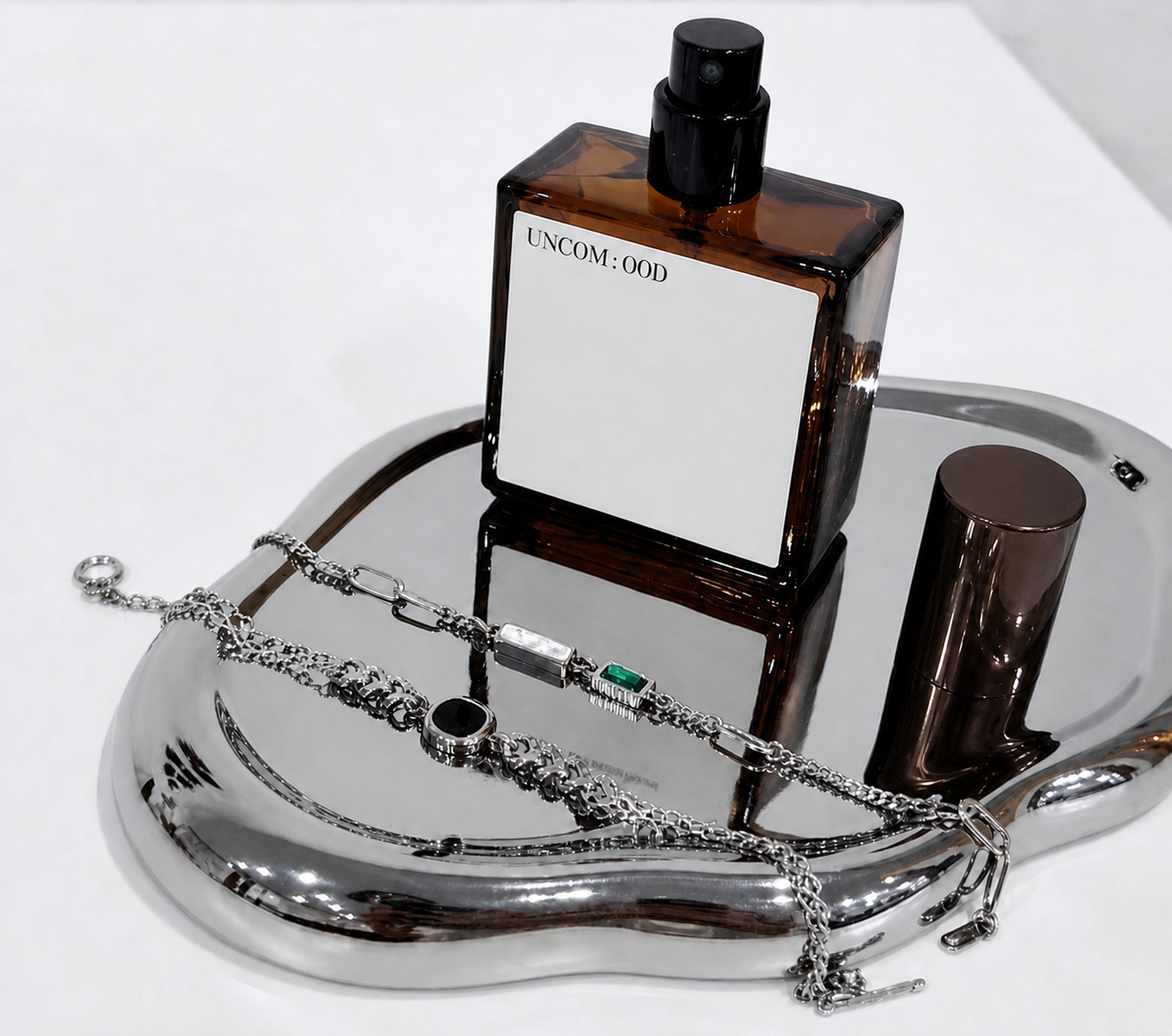 A bracelet and UNCOMOOD scent bottle styled on a reflective tray